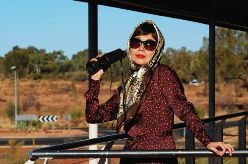 A well dressed woman looks out from a verandah at the landscape from Sails Resort